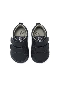 Zwarte kinderschoenen met een zachte stoffen bovenkant, veilige klittenbandstraps, een ronde neus, en een gevoerde binnenzool met een voetafdruk.
