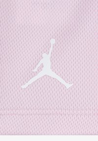 Biela silueta basketbalistu skákajúceho s loptou na svetloružovom textúrovanom látkovom pozadí.