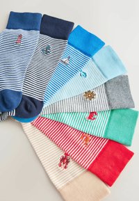 Sept paires de chaussettes rayées de différentes couleurs, chacune avec un petit motif brodé nautique ou animal marin près du poignet.