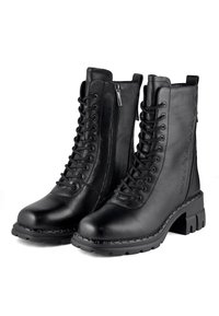 Botas de tobillo de cuero negro con cordones en la parte delantera, cremallera lateral y suela de goma gruesa. Textura suave con refuerzos en la puntera y el talón.