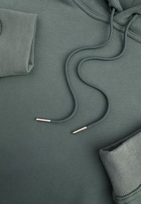 Olijfgroene hoodie met ribbels aan de manchetten, voorzien van verstelbare trekkoorden en metalen aglets, gemaakt van zachte, gestructureerde stof.
