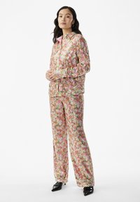Floral-patterned two-piece set in pastel colors, featuring a zip-up jacket and loose-fitting pants, made from textured fabric with a glossy finish.