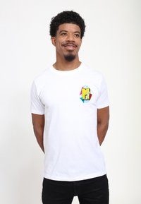 Hvid bomulds t-shirt med et multikolor MTV-logo på venstre bryst. Korte ærmer, rund halsudskæring, glat tekstur.