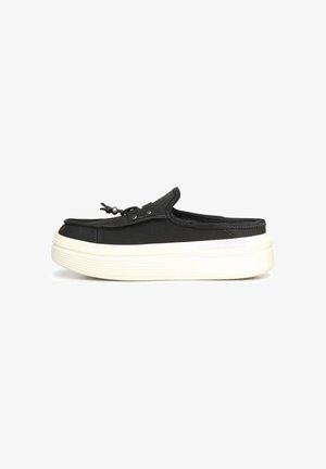 Zueco negro sin talón con suela de plataforma blanca y gruesa y cordón decorativo con ajuste de tope en la parte superior, mostrado de lado sobre fondo blanco.