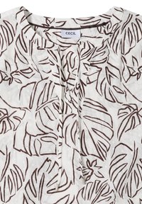 Blouse blanche avec imprimé abstrait de feuilles marron, encolure ronde, détail noué à l'avant et étiquette de marque « CECIL » à l'intérieur du col.