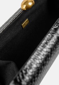 Black textured fabric clutch with a snakeskin pattern, featuring a gold metallic clasp and a small brand label inside.