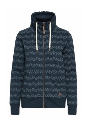 Sweat à capuche zippé bleu marine avec un col haut, des motifs en zigzag blancs, des poches avant et des accents de cordon de serrage. Fabriqué en tissu doux.