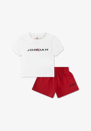 Fehér pamutpóló fekete "JORDAN" logóval és piros sziluettel. Piros pamut rövidnadrággal, fekete "JORDAN" részlettel kísérve.