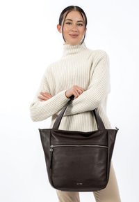 Bruine leren draagtas met een gladde textuur, voorzien van een ritssluiting aan de voorkant en dubbele handgrepen voor gemakkelijk dragen.