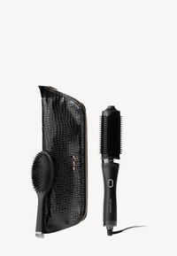 Een set haarstylingtools met zwart haar, inclusief een ronde borstel, een cilinderborstel met haren en een zwart nepleren etui met krokodillenpatroon en gouden accenten.
