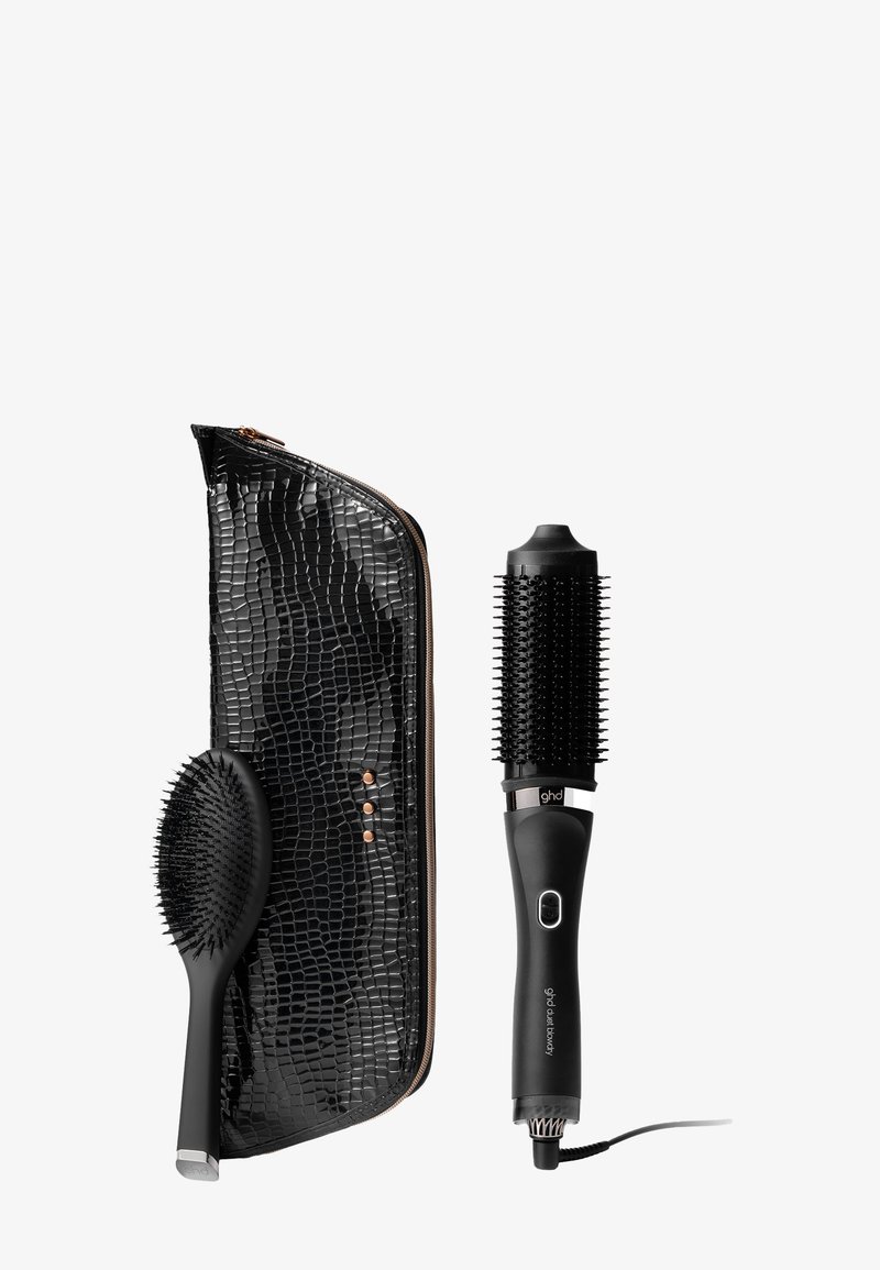 Een set haarstylingtools met zwart haar, inclusief een ronde borstel, een cilinderborstel met haren en een zwart nepleren etui met krokodillenpatroon en gouden accenten.