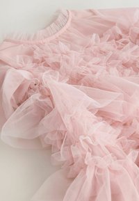 Roza zgornji del iz tila z nabrano teksturo, elastičnim izrezom in plastmi. Mehka, lahka tkanina s prosojnim videzom.