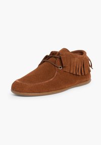 Bruine suède moccasin-stijl pantoffel met franjes, ronde neus en vetersluiting. Zachte textuur en flexibele rubberen zool.