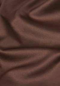 Tissu brun lisse et brillant avec des plis subtils et une fine texture côtelée reflétant une lumière douce.