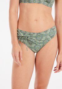 Zelené bikiny s upevňovacími šnúrkami po bokoch, zdobené geometrickými vzormi v rôznych odtieňoch zelenej, bielej a žltej.