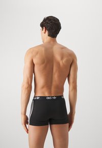 Schwarze Boxershorts mit einem elastischen Bund und Markenzeichen, mit drei weißen Streifen auf jeder Seite, glattem Stoff und einer anschmiegsamen Silhouette.