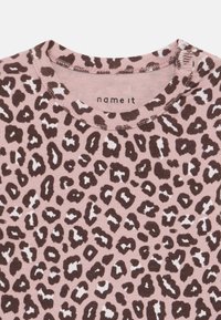 Kurzärmliges Top in Hellrosa mit einem braun-weißen Leopardenmuster. Verfügt über einen gerippten Halsausschnitt und einen weichen, strukturierten Stoff.