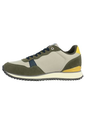 Zapatilla verde y beige con parte superior de ante y tela texturizada, cordones azul marino y acentos amarillos en el talón. Suela de goma con patrón de agarre.