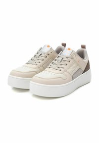 Zapatillas de piel beige con detalles en blanco, punta redondeada, cuello acolchado y suela gruesa blanca. Presenta paneles laterales grises y marrones.