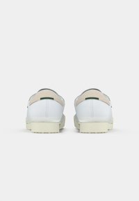 Sapatos de couro brancos com um suave destaque em bege no salto. Projetados com uma sola de borracha e discretos detalhes verdes na parte de trás.