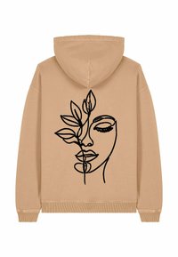 Felpa beige con un design a contorno di un volto e foglie nere sul retro. Tessuto morbido con una vestibilità comoda e cappuccio con cordini.