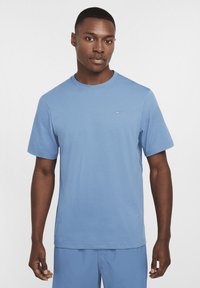 Light blue crew-neck t-shirt made of smooth, breathable fabric. Short sleeves with a small, white Nike swoosh on the left chest.