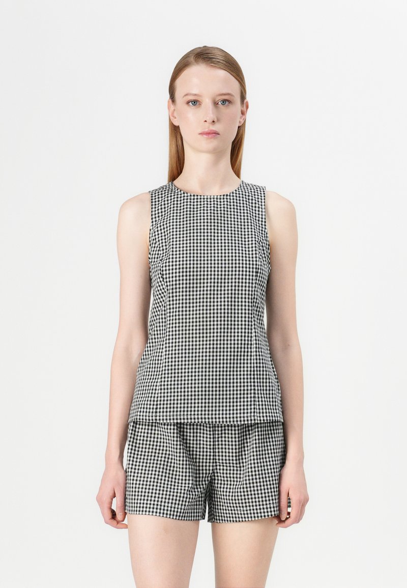 Schwarze und weiße Gingham-Ärmelose Bluse mit Rundhalsausschnitt, kombiniert mit passenden Shorts. Glattes Material, lockere Passform, schlichtes Design.