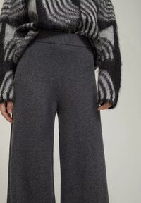 Graue, weit geschnittene Hosen aus weichem Stoff mit glatter Textur. Sie verfügen über einen hohen elastischenBund und haben keine sichtbaren Muster oder Akzente.