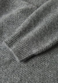 Kadar bliza sivi pleteni rukav džempera s rebrastim zapešćem i teksturiranom vunenom tkaninom.