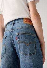 Levi's blå denimjeans med ljus tvätt. Har två bakfickor, synlig sömnad och en tan läderetikett i midjan.