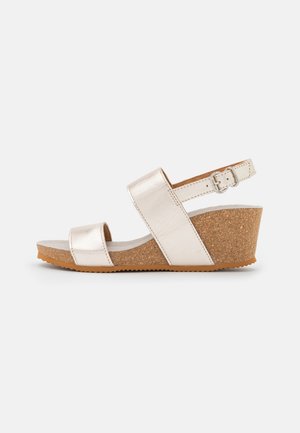 Beige kile sandal med korksål, to brede remme og en justerbar ankelspænde på hvid baggrund.