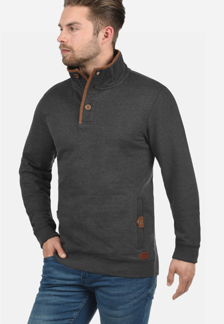 Dark gray pullover made of soft fabric, featuring a high collar, brown button details, and side pockets with leather accents.