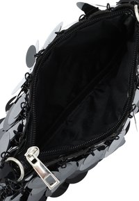 Borsa nera con paillettes dal rivestimento lucido. Presenta una chiusura con zip e un interno in tessuto nero liscio. Design compatto per una facile conservazione.