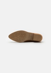 Suela de zapato marrón con un patrón floral texturizado, punta redondeada y un ligero tacón. Superficie suave con un detalle intrincado.