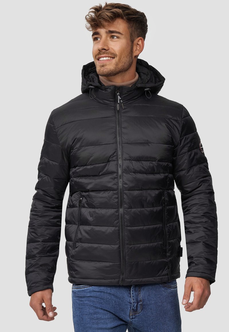 Veste rembourrée noire à fermeture éclair avec une capuche, dotée de sections cousues horizontalement, de deux poches latérales et de cordons de serrage réglables.