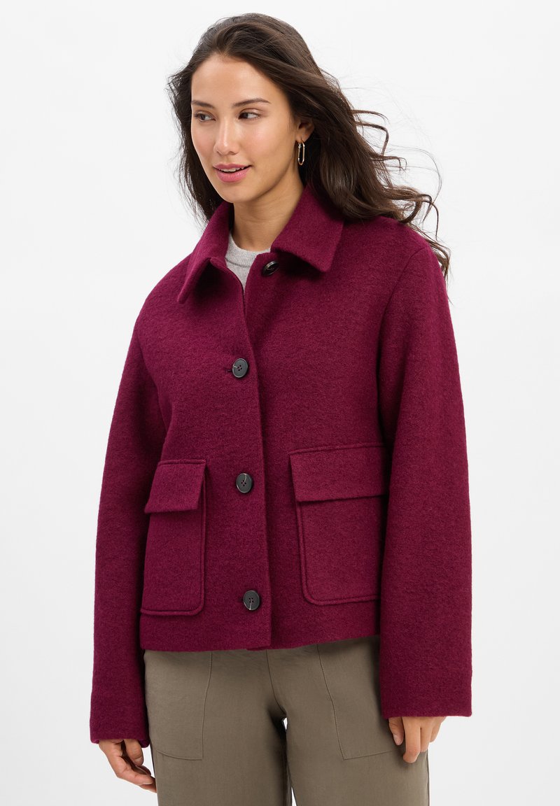Burgundy wool blend jacket with a collared neckline, front button closure, and two patch pockets. Features a textured surface and loose fit.