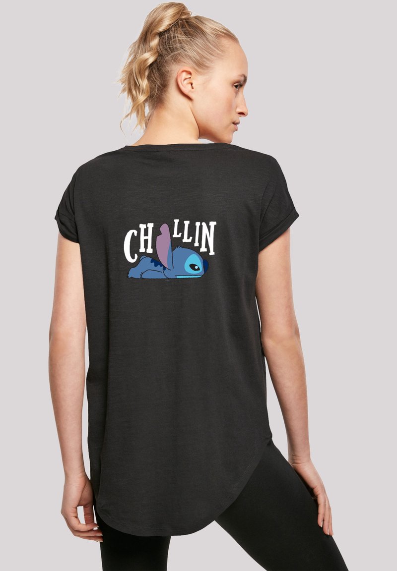 Camiseta negra de manga corta con dobladillo redondeado. Presenta el texto "CHILLIN" y un personaje de dibujos animados azul tumbado en la espalda.