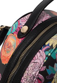 Sac à dos floral multicolore en cuir noir texturé, avec une fermeture éclair dorée et des accents dorés, orné de motifs de roses vibrants sur fond sombre.