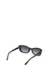 Gafas de sol negras estilo cat-eye con lentes degradados, montura de plástico brillante y brazos con marca. Forma distintiva y textura suave.