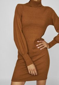 Abito lavorato a maglia color ruggine con colletto alto, polsini a coste e silhouette aderente. Tessuto testurizzato con maniche lunghe e a sbuffo.