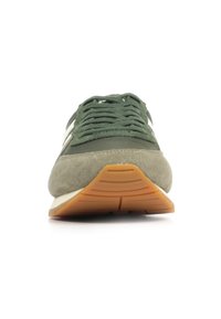 Sneaker verde in suede con superficie testurizzata, chiusura con lacci e suola in gomma a contrasto con un motivo arancione.