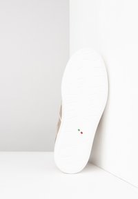 Leather sneaker with a textured beige upper and a white rubber sole. Features subtle accents. The heel shows a small Italian flag detail.