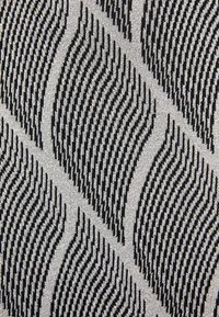 Tissu tricoté géométrique noir et blanc avec des formes losanges rayées répétées créant un motif d'illusion d'optique en 3D.