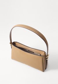 Sac à main en cuir fauve avec une texture lisse, une forme fine et une seule bandoulière. Il comprend un compartiment zippé et des coutures contrastées.