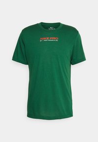 Camiseta Nike Pro de manga corta verde con el texto rojo y blanco "NIKE PRO PRODUCT ENGINEERED BY NIKE" en el pecho.
