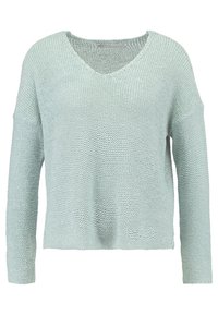 Světlé zelený pletený svetr s výstřihem do V, dlouhými rukávy a volnějším střihem. Texturovaná tkanina s žebrovanými detaily na manžetách a spodním lemu.
