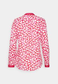 Camicia a maniche lunghe con motivo a ciottoli rosa e bianchi. Presenta un colletto rosso solido e accenti sul polsino. Tessuto leggero con una texture liscia.