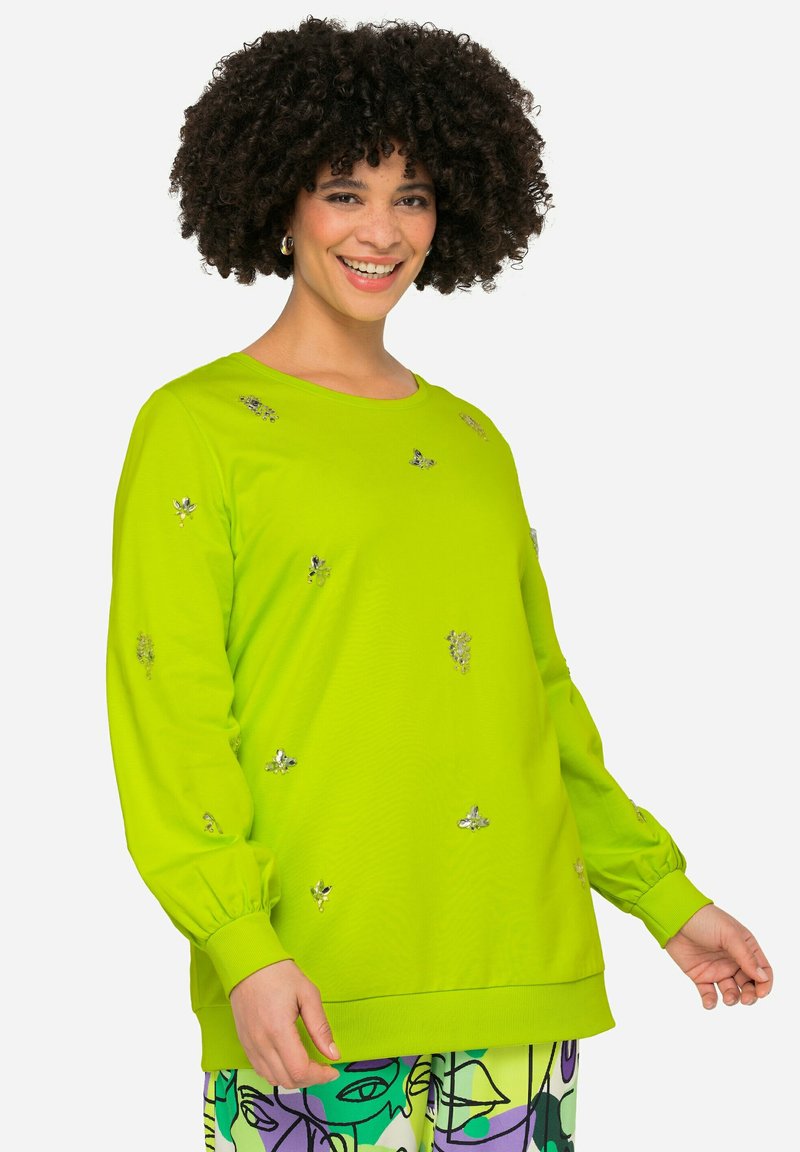 Sudadera verde lima de tela suave, cuenta con acentos florales bordados, mangas largas con puños fruncidos y un corte relajado.