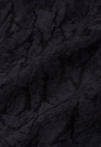 Tissu noir texturé avec une surface légèrement froissée, présentant un mélange de zones lisses et rugueuses, affichant des motifs subtils tout au long.