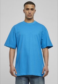 Tricou oversized din bumbac albastru, cu mâneci scurte, guler rotund și croială relaxată. Textură netedă, fără modele sau accente.
